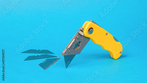 Folding knife cutter and three spare blades on a blue background. © kvladimirv