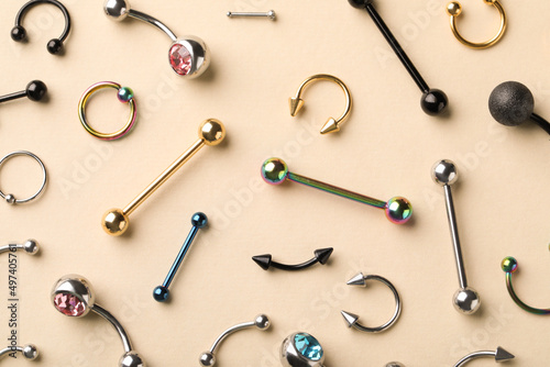 Stylish jewelry for piercing on beige background, flat lay photo