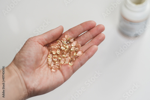 Yellow pills of vitamin d3 in woman's hand on white background photo