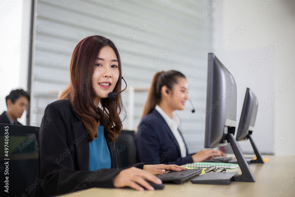Young Asian business call center man and woman with headset sitting in office desk using computer. work for telemarketing. consulting service or customer support. operator agent giving advice on phone