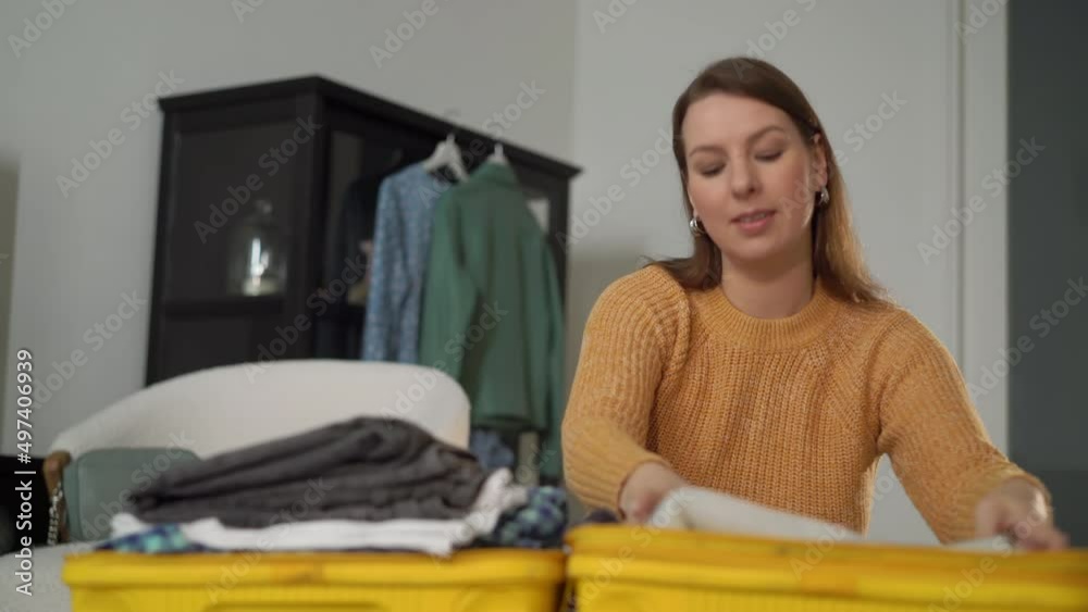A young woman is packing her suitcase. Yellow plastic travel bag. A young woman is packing her suitcase. Yellow plastic travel bag.