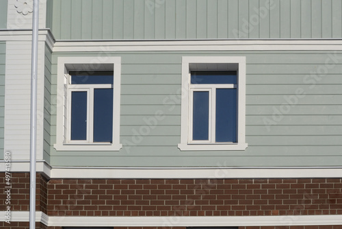 Front view of 2 windows on a new grey-blue faux plank wall with decorative elements