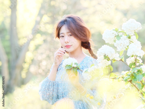 Portrait of elegant Chinese girl in dress enjoy carefree time in forest park in sunny day. Outdoor fashion portrait of glamour young Chinese cheerful stylish woman.