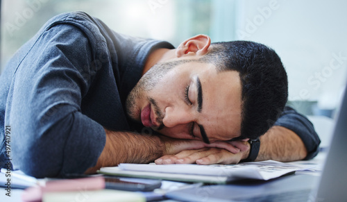 Im just going to sleep on my problems. Shot of a young businessman feeling exhausted and sleeping on his desk in his office.
