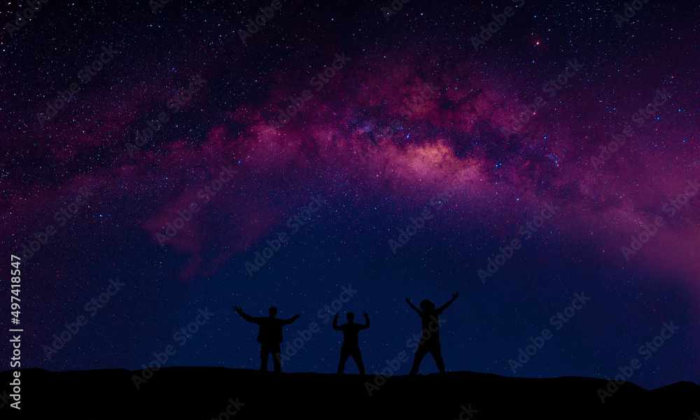 A group of people are happily standing next to the Milky Way galaxy pointing at a bright star.