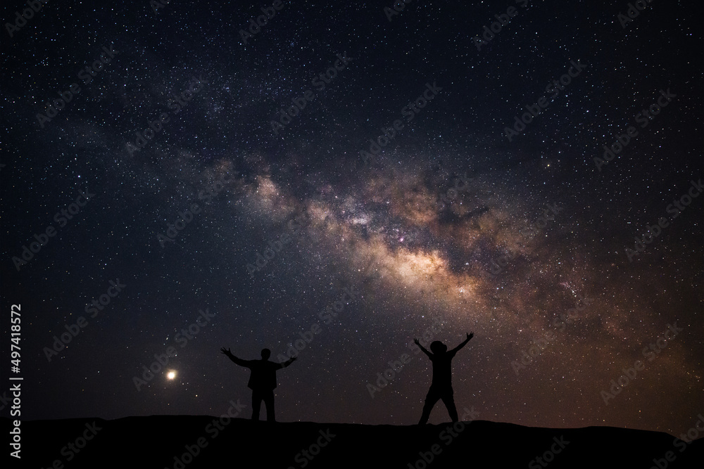 Two men happily stood beside the Milky Way Galaxy and pointed to a bright star.