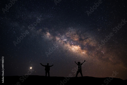 Two men happily stood beside the Milky Way Galaxy and pointed to a bright star.
