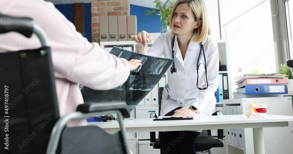 Doctor discusses x-ray of the spine with disabled patient Doctor discusses x-ray of the spine with disabled patient