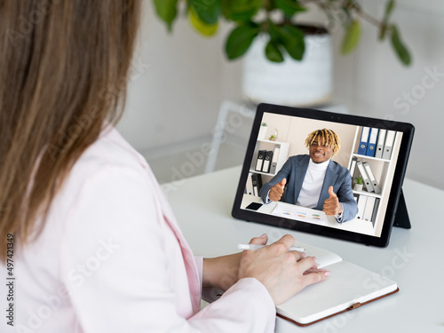 Web call. Online negotiation. Corporate telework. Female CEO discussing agreement with satisfied business partner showing deal gesture on tablet screen in digital office.