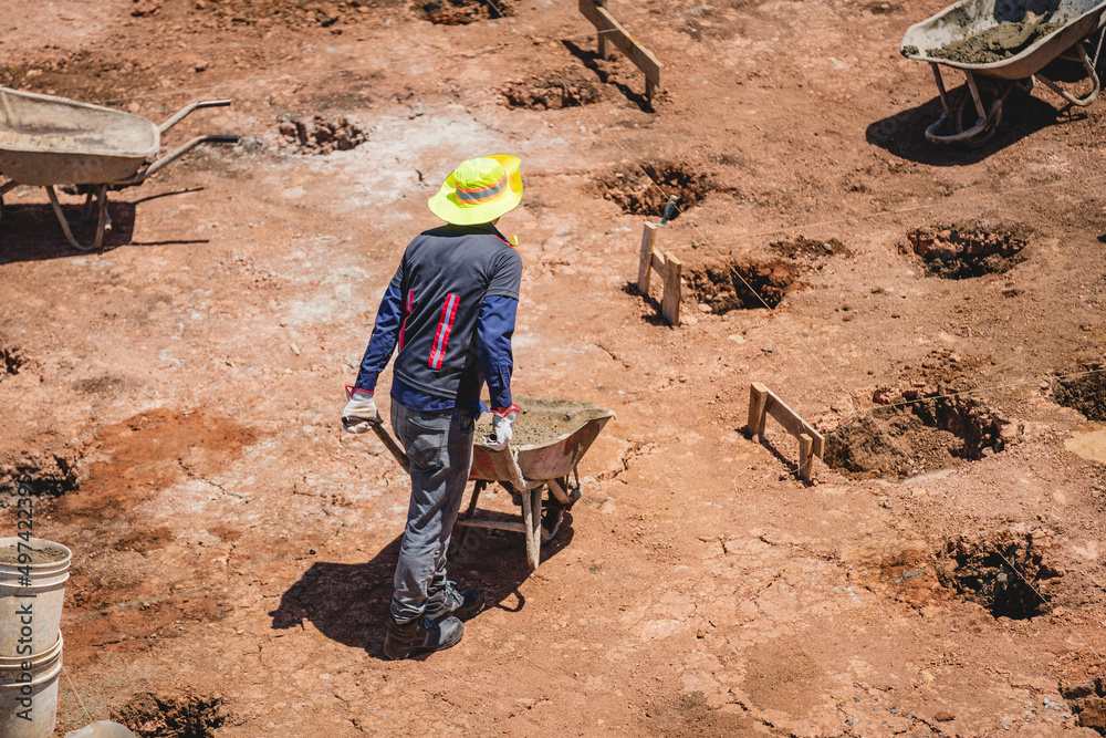 Unknown man with a wheelbarrow working in a construction site Unknown man with a wheelbarrow working in a construction site