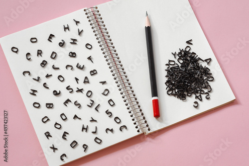 black latin letters randomly scattered on a blank page of a notebook, the concept of grammar, creativity in writing and journalism photo