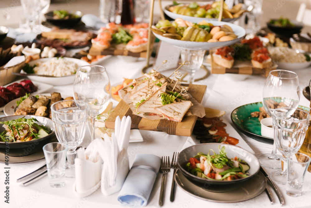 Beautifully decorated catering banquet table with different food snacks and appetizers with sandwich, caviar, fresh fruits on corporate party event or wedding celebration