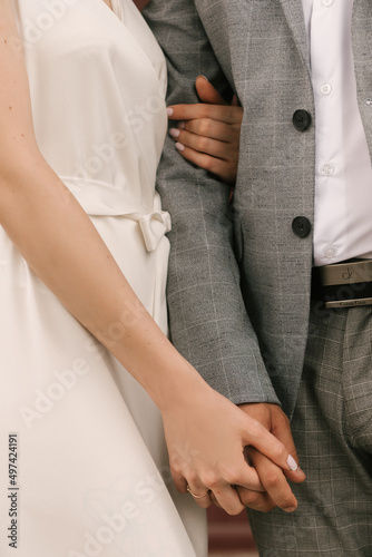The bride and groom embrace, hands close-up