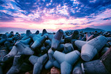 Ocean landscape at sunset with gray tetrapods at the seashore or coastal protection from breakwaters
