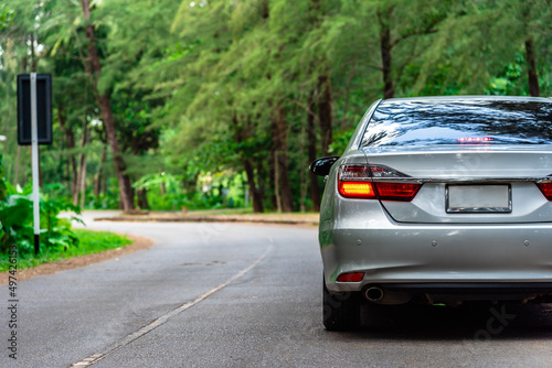 Rear view of car going on the green forest road with break light, car travel and transportation concept.
