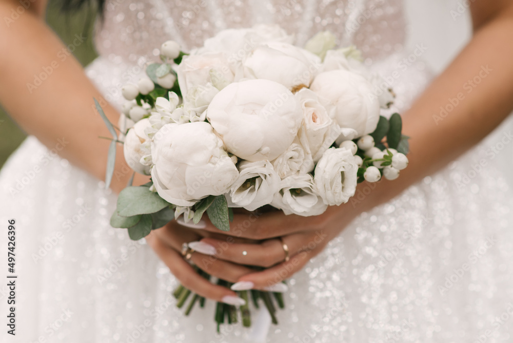 A luxurious wedding bouquet with white peonies in the hands of the bride A luxurious wedding bouquet with white peonies in the hands of the bride
