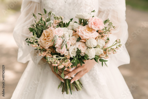 A luxurious wedding bouquet in the shape of a heart in the hands of the bride