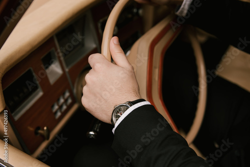 Details of the groom, male hands on the steering wheel of a retro car