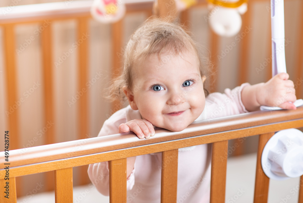 Portrait of a laughing baby who is standing in a crib Portrait of a laughing baby who is standing in a crib