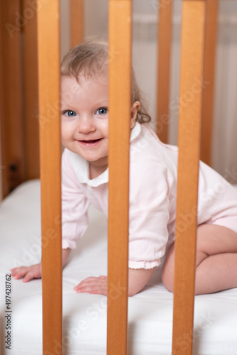 Portrait of a laughing little girl who is in a crib