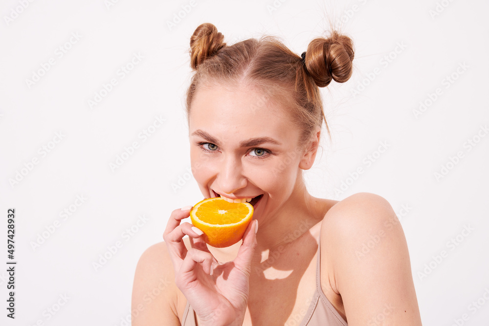 Pretty charming joyful attractive cheerful funny comic positive nude natural pure girl having two pieces of orange, closing one eye, isolated on beige background with copy space for advertisement