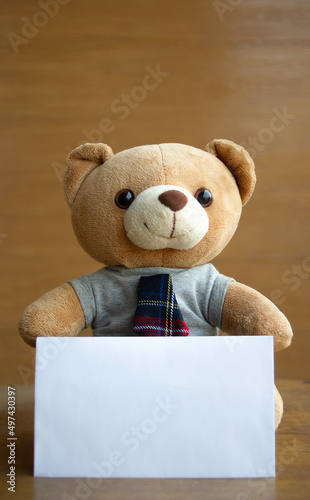 Portrait portrait brown teddy bears and white blank paper on brown wooden background. Birthday or anniversary card concept.