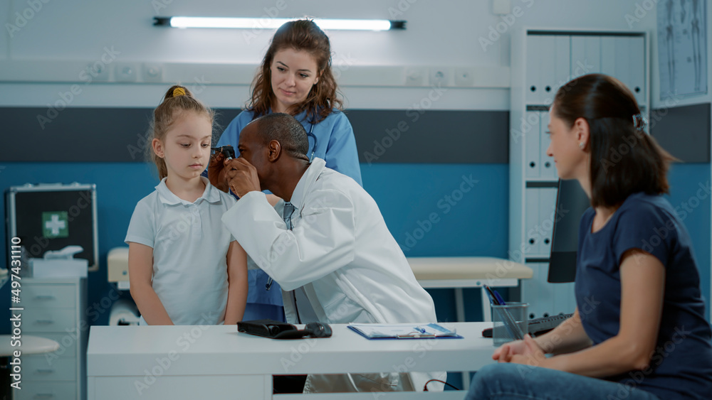 Obraz premium Physician using otoscope on small child to do ear examination in office. Health specialist consulting girl with otoscopy instrument to check infection, otologist doing checkup exam.