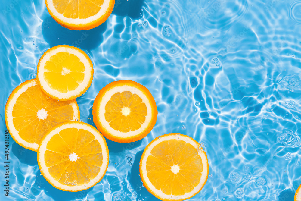Creative summer composition made of sliced orange in transparent pool water. Refreshment concept. Healthy refreshing drink theme. Top view Creative summer composition made of sliced orange in transparent pool water. Refreshment concept. Healthy refreshing drink theme. Top view