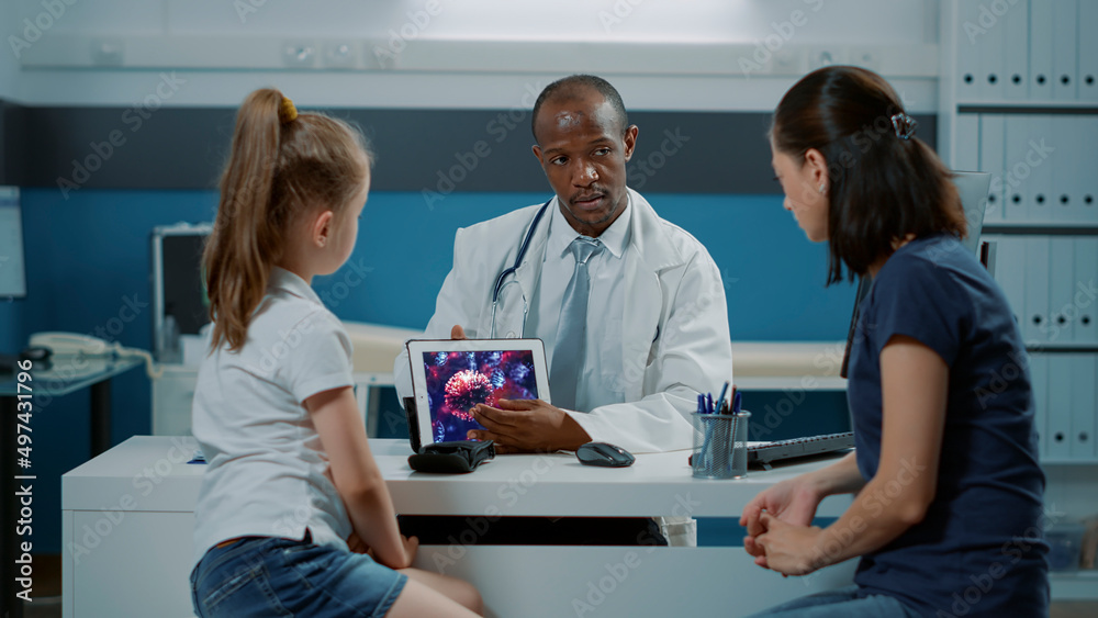 Health specialist showing virus illustration on digital tablet to woman and girl. Pediatrician explaining coronavirus animation on gadget screen, giving advice to mother and child in office.
