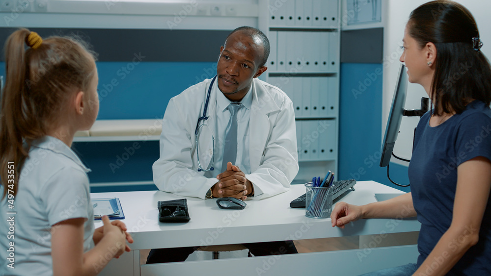 Obraz premium Medic discussing with small child and parent at appointment visit in office. Specialist having conversation with mother and little girl about health care service at consultation.