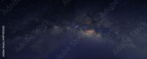 Milky way in the night sky and stars on dark background with noise and grain. Photo taken with long exposure and white balance selected. 