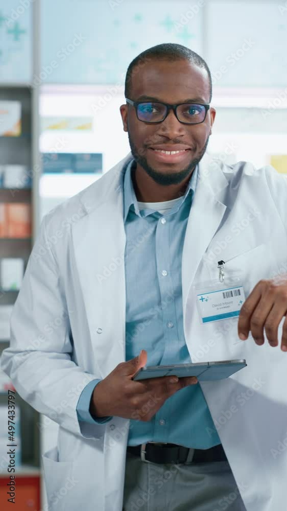Pharmacy: Portrait of Professional Confident Black Pharmacist Uses Digital Tablet Computer, Checks Inventory of Medicine, Looks at Camera and Smiles Charmingly. Drugstore with Health Care Products Pharmacy: Portrait of Professional Confident Black Pharmacist Uses Digital Tablet Computer, Checks Inventory of Medicine, Looks at Camera and Smiles Charmingly. Drugstore with Health Care Products