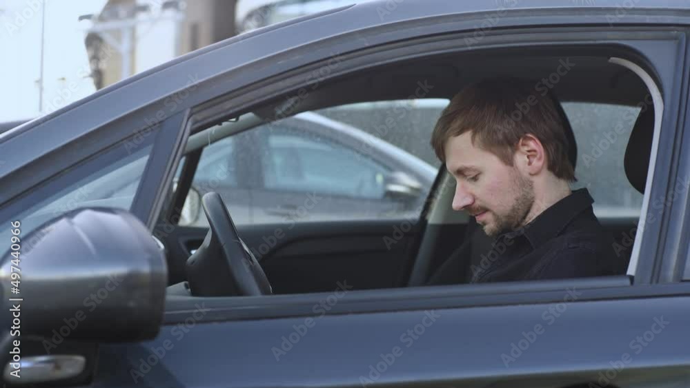 A man in a rage sitting in a car. Enraged driver hits the steering wheel. A man in a rage sitting in a car. Enraged driver hits the steering wheel.