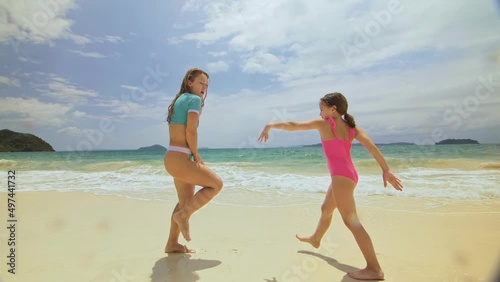 The happy fun woman with her child enjoying her outdoor vacation on tropical island. The optimistic funny mother with daughter dancing on shallow ocean. Concept summer holidays, dance beach party