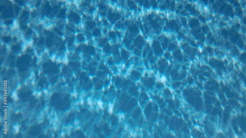 Slow motion, Glare of sunlight on the blue bottom of the pool. Natural background with sunbeams at the bottom of the blue pool. Slow motion, Glare of sunlight on the blue bottom of the pool. Natural background with sunbeams at the bottom of the blue pool.