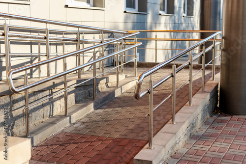 A ramp and metal railings at the entrance to the residential building for the convenience of people with disabilities and the elderly.