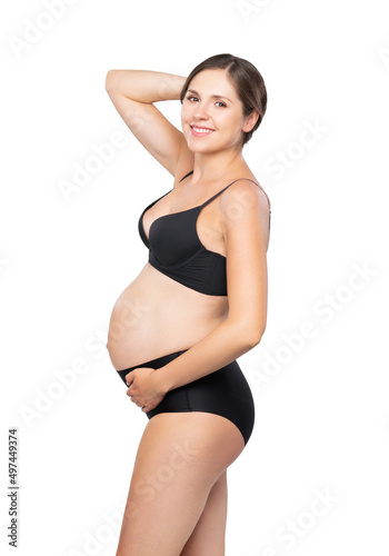 Young pregnant woman in black swimsuit. Girl expecting a baby and touching her belly isolated on white background.