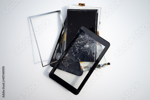 A broken electronic tablet on a white isolate. Repair of mobile equipment.Replacement of glasses on the phone. photo