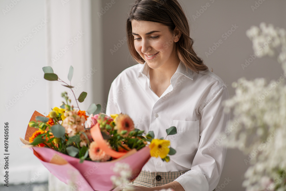 people, gardening and floral design concept - happy smiling woman or floral artist with bunch of flowers at home