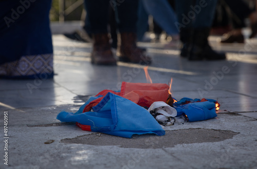 SYNTAGMA SQUARE, ATHENS, GREECE - April 3rd, 2022: Torn to pieces and set on fire Russian flag lying on the sidewalk at protest against the WAR in UKRAINE.