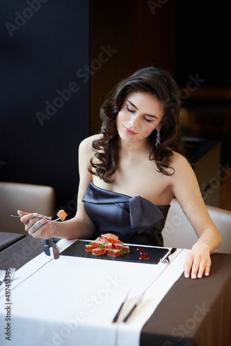 Sensual brunette in an evening dress, serves a dessert in the restaurant, dressed in a dress, makeup and hairstyle.