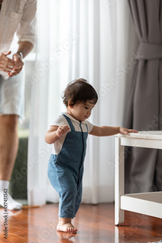 cute toddler little child family concept, baby learning to walk with father and mother to help care and holding hand, first step with childhood parent support, small love portrait little boy at home