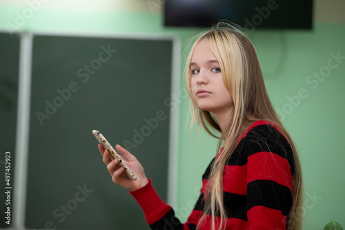 Teenager of senior school age. A teenage girl stands in front of a blackboard. photo