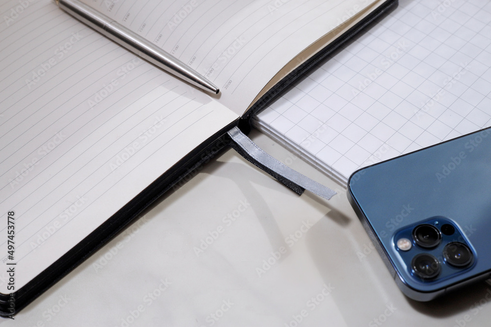 Fototapeta premium Communication technologies. On the table is a mobile phone, a diary, a pen.