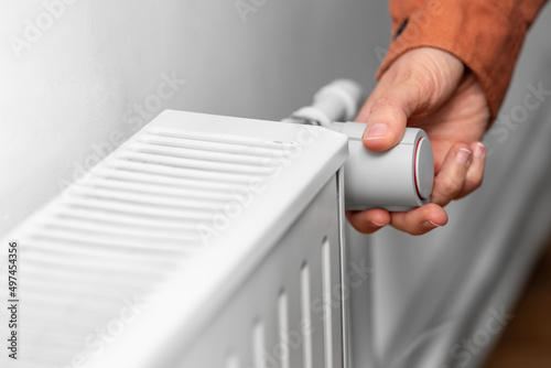 Obraz na plátne heating, energy crisis and consumption concept - close up of hand turning radiat