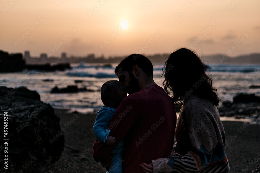 Silhouette of a traditional structured family on the beach enjoying a sunset in Asturias, Spain