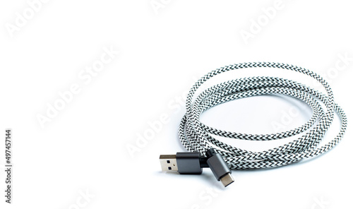 USB data cable with fabric braid rolled up on white, isolated close-up, space for text.