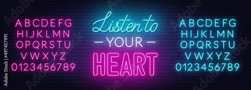 Listen to your heart neon lettering on brick wall background.