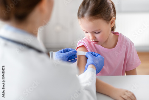 medicine, healthcare and vaccination concept - female doctor or pediatrician talking to little girl patient on medical exam at clinic