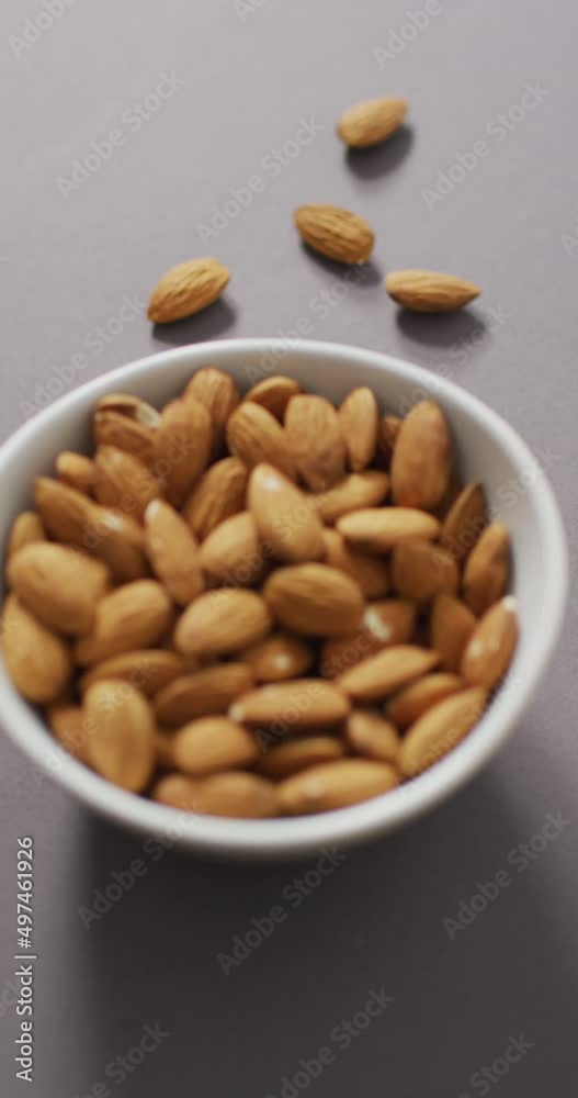 Vertical video of a bowl of almonds on a lilac background Vertical video of a bowl of almonds on a lilac background